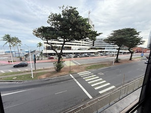 Un edificio de varios pisos con estacionamiento, un paso de peatones y vista al mar.