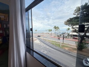 A view through a window of a street with palm trees, a road, and a building in the background.