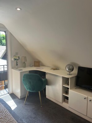 A room with a desk, a teal chair, a globe, a TV, and a guest book. - Treetop Private  studio (tiny house) (Farnborough)