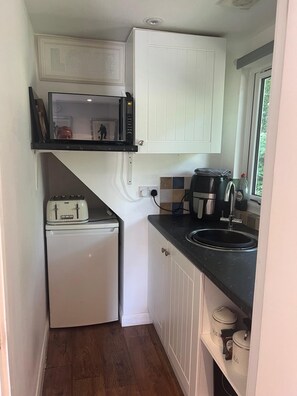 A compact kitchen with a microwave, toaster, and sink. - Treetop Private  studio (tiny house) (Farnborough)