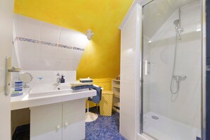 Une salle de bain avec un lavabo blanc, un miroir et une douche à parois de verre.