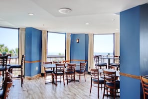 A restaurant with wooden tables and chairs, blue walls, and large windows with curtains. - Direct Oceanfront 1BR w/Beach Access-Resort Pools (Myrtle Beach)