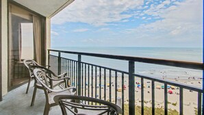 A balcony with chairs overlooking a beach. - Oceanfront 1BR Suite + Beach Access + Lazy River (Myrtle Beach)