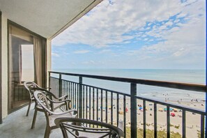 A balcony with chairs overlooking a beach. - Oceanfront 1BR Suite + Beach Access + Lazy River (Myrtle Beach)