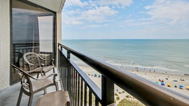 A balcony with a view of the beach, outdoor furniture, and a railing. - Oceanfront 1BR Suite + Beach Access + Lazy River (Myrtle Beach)