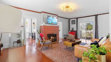 A living room with a fireplace, a sofa, a coffee table, and a TV mounted on the wall.