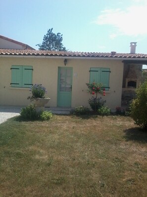 A two-story building with a tiled roof, a green door, and shutters. - Cottage "Little House in Coulon, Marais Poitevin" (Coulon)