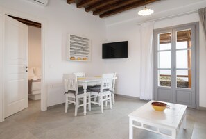 A room with a dining table, chairs, a television, and a window with a view.