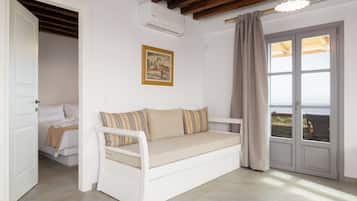 Quarto com um sofá branco, um quadro na parede e uma porta que dá para uma varanda.