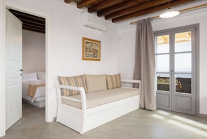 Une pièce avec un canapé blanc, un tableau accroché au mur et une porte donnant sur un balcon.