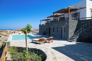 A stone building with a pool, lounge chairs, and a view of the sea. - T' Aeri Sifnos (Sifnos)