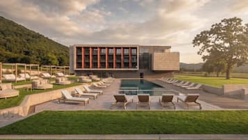 A modern building with a pool and lounge chairs.