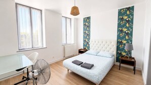 A bedroom with a bed, a desk, a chair, a standing fan, a lamp, and a window. - 4-bedroom family home with a garden and easy parking, just outside Toulouse (Aucamville)
