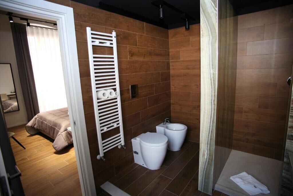 Une salle de bain moderne équipée d’une douche, de deux toilettes et d’un porte-serviettes.