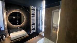 A modern bathroom with a marble vanity, a glass shower enclosure, and a built-in towel rack.