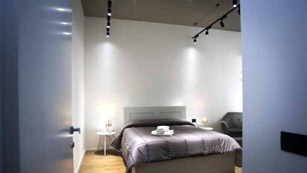 A modern bedroom with a large bed, bedside lamps, and a chair.