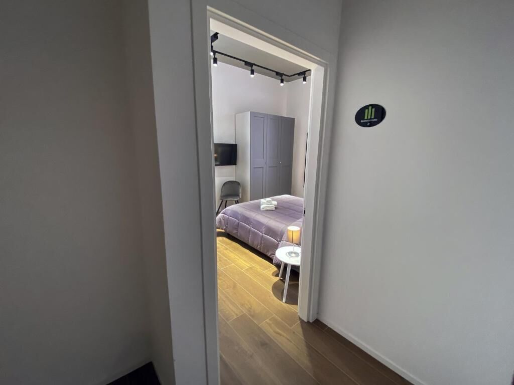 Un couloir étroit mène à une chambre qui contient un lit, une chaise et une petite table.
