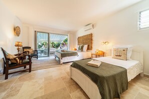 Ein Schlafzimmer mit Bett, Stuhl, Tisch und Blick ins Freie.