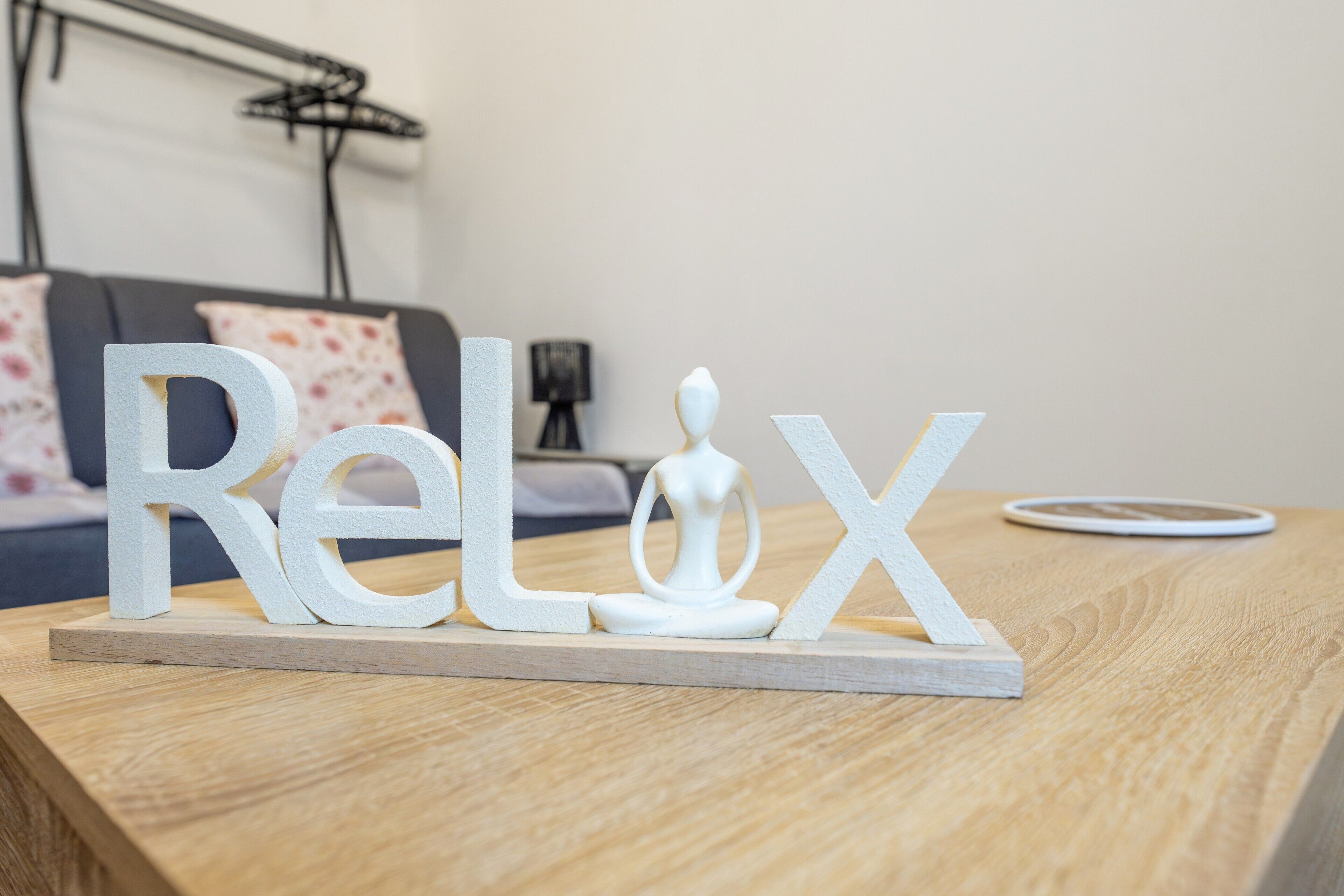 Ett träbord med vita bokstäver som bildar ordet ”Relax” och en vit staty på ett piedestal.