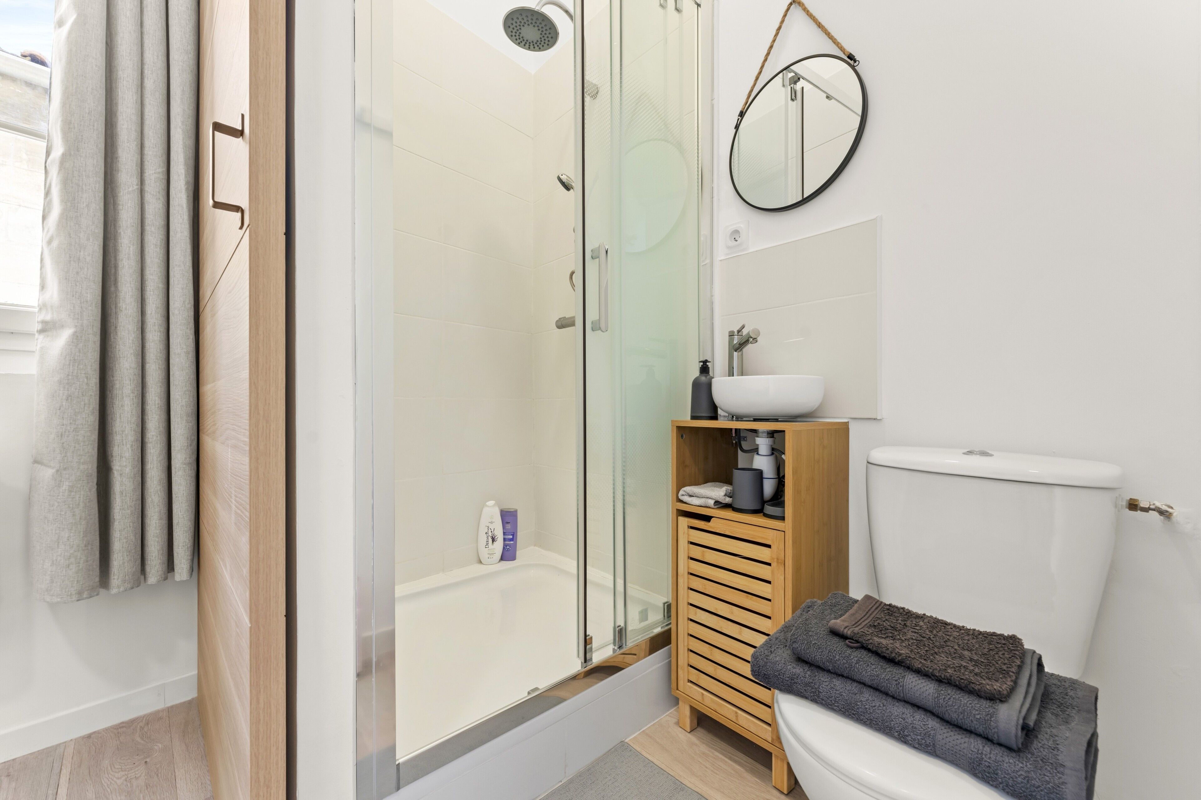 Une salle de bain moderne avec une douche à parois de verre, des toilettes, un lavabo avec un miroir et un meuble en bois.