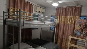 A bunk bed room with a window, curtains, and a ceiling fan. - GROUND-FLOOR HOUSE—GARDEN—ROOMS FOR RENT AND A TERRACE WITH A PING-PONG TABLE (Rivière-Salée)