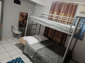 Ein Schlafraum mit Etagenbetten, Schreibtisch, Stuhl und einem Bild an der Wand.
