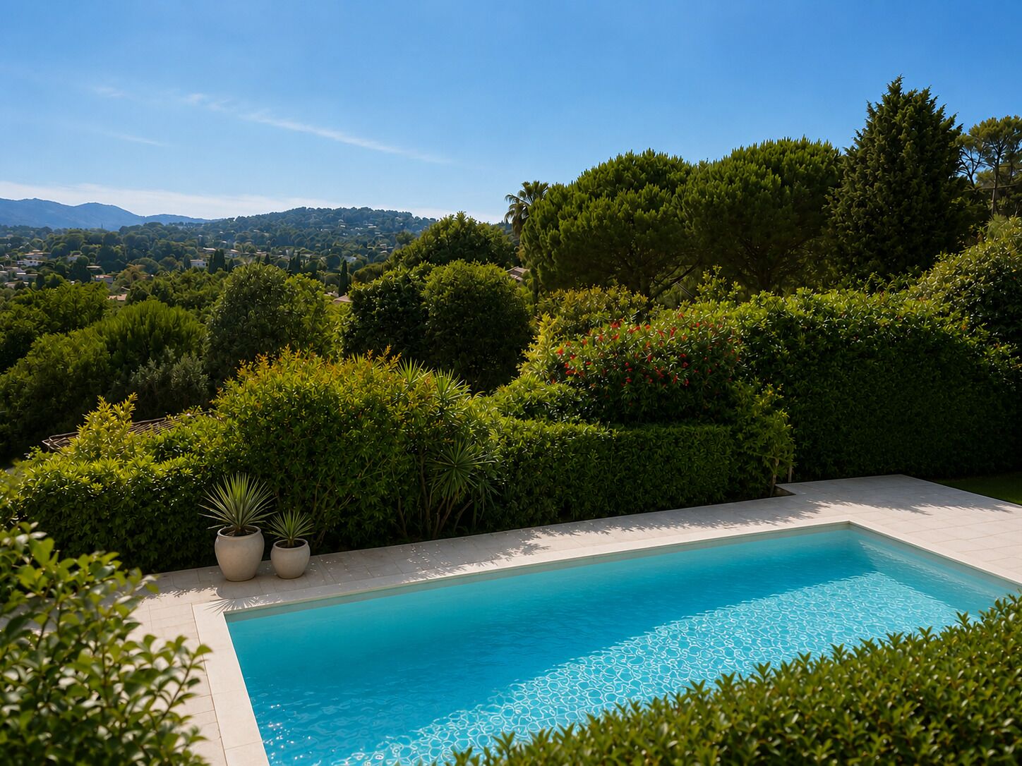 A rectangular pool with a clear blue water surface, surrounded by well-maintained hedges and potted plants.