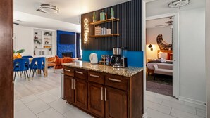 A modern kitchen with a built-in island, wooden cabinets, and a coffee station.
