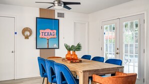 A dining area with a wooden table, blue and orange chairs, a ceiling fan, and a 'TEXAS' sign on the wall.