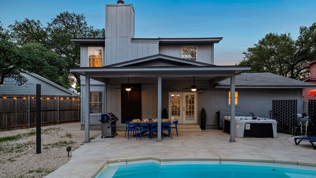A house with a covered patio, a swimming pool, and a hot tub.