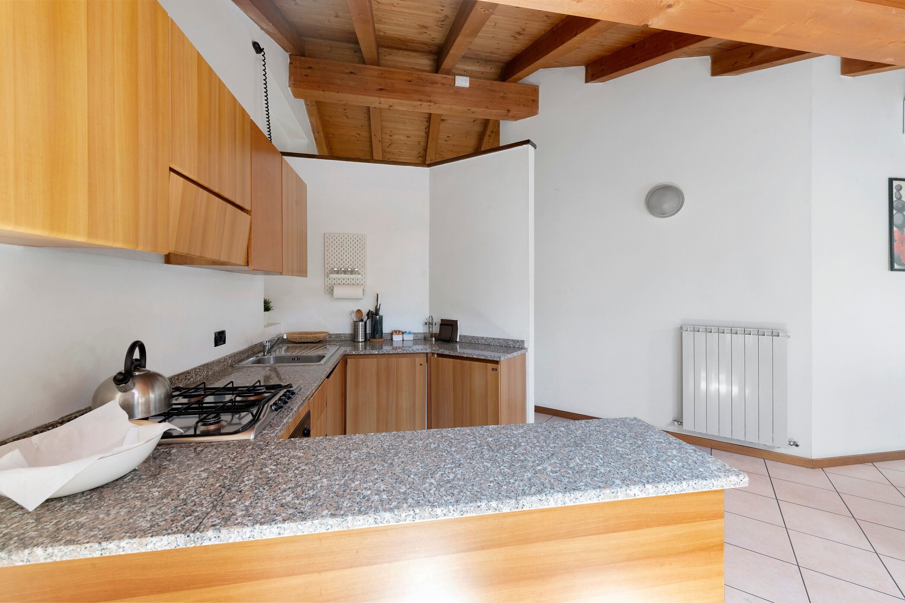 Eine Küche mit Holzausstattung, einer Granit-Arbeitsplatte, einem Gasherd und einem weißen Heizkörper.