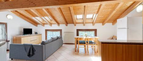 Ein modernes Interieur mit Holzbalkendecke, einer Couch, einem Esstisch und einer Küchenzeile.