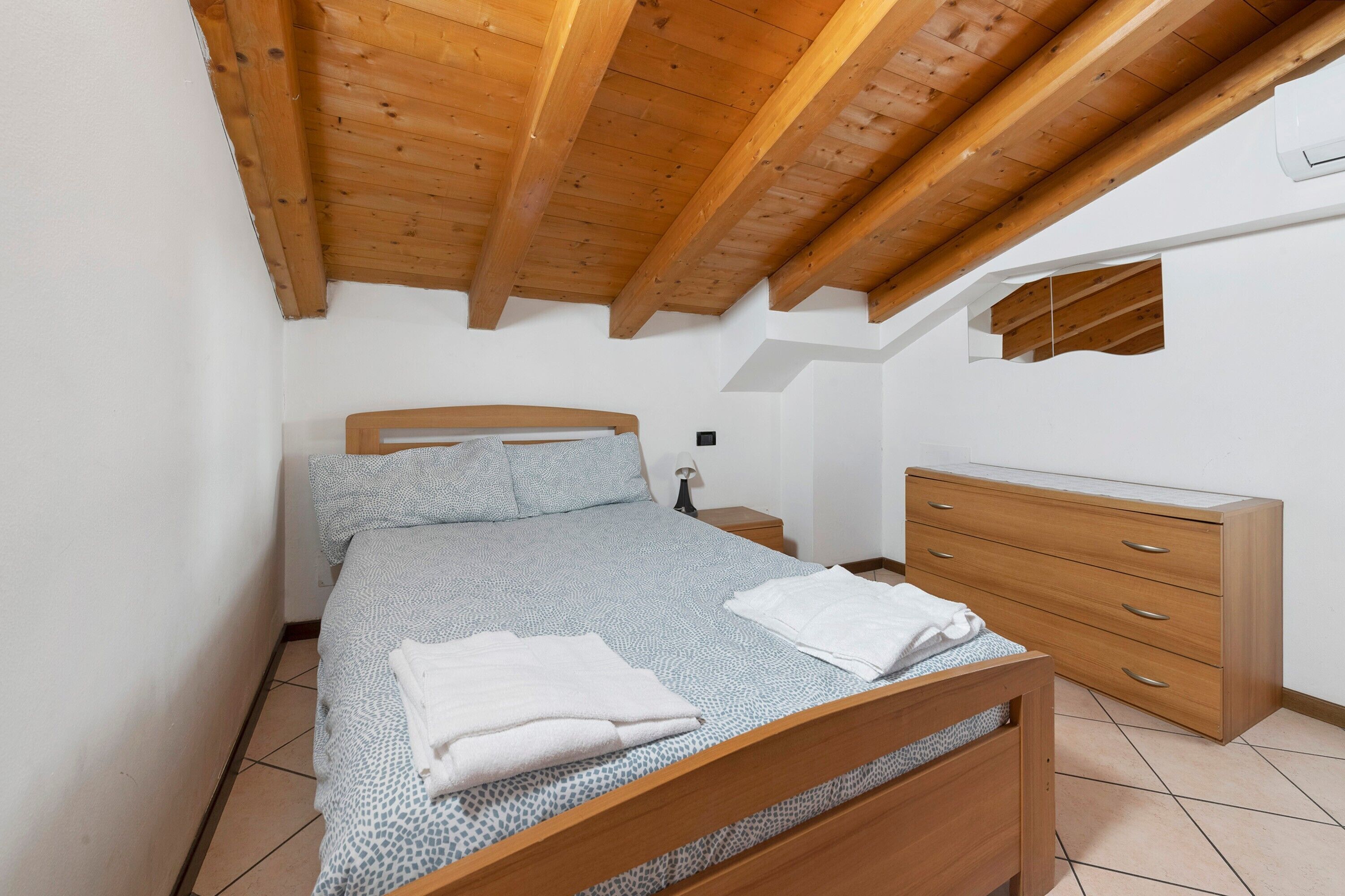 Un dormitorio con una cama de madera, un aparador de madera y una mesita de noche con una lámpara.