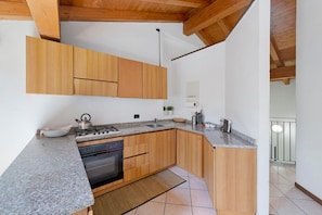 A kitchen with wooden cabinets, granite countertops, a stove, and a sink.