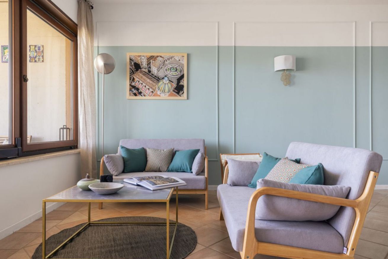A living room with a sofa, armchair, coffee table, and a painting on the wall.