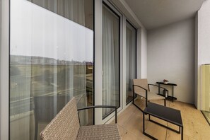 Ein Balkon mit Blick auf Gebäude, ein Stuhl, ein kleiner Tisch und eine Couch.