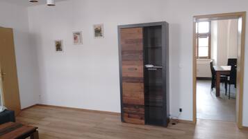 Una habitación con piso de madera, una puerta alta con panel de vidrio, una mesa de comedor con sillas y una lámpara colgante.