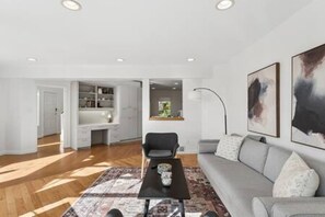 Ein modernes Wohnzimmer mit einer Couch, einem Couchtisch und Blick in die Küche.