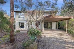 A modern house with a covered patio, surrounded by trees and a gravel driveway. - Awel -Y- Mor (Moggs Creek)