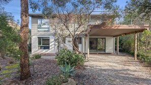 A modern house with a covered patio, a gravel driveway, and a garden with a tree and shrubs. - Awel -Y- Mor - Pet friendly beach retreat (Moggs Creek)