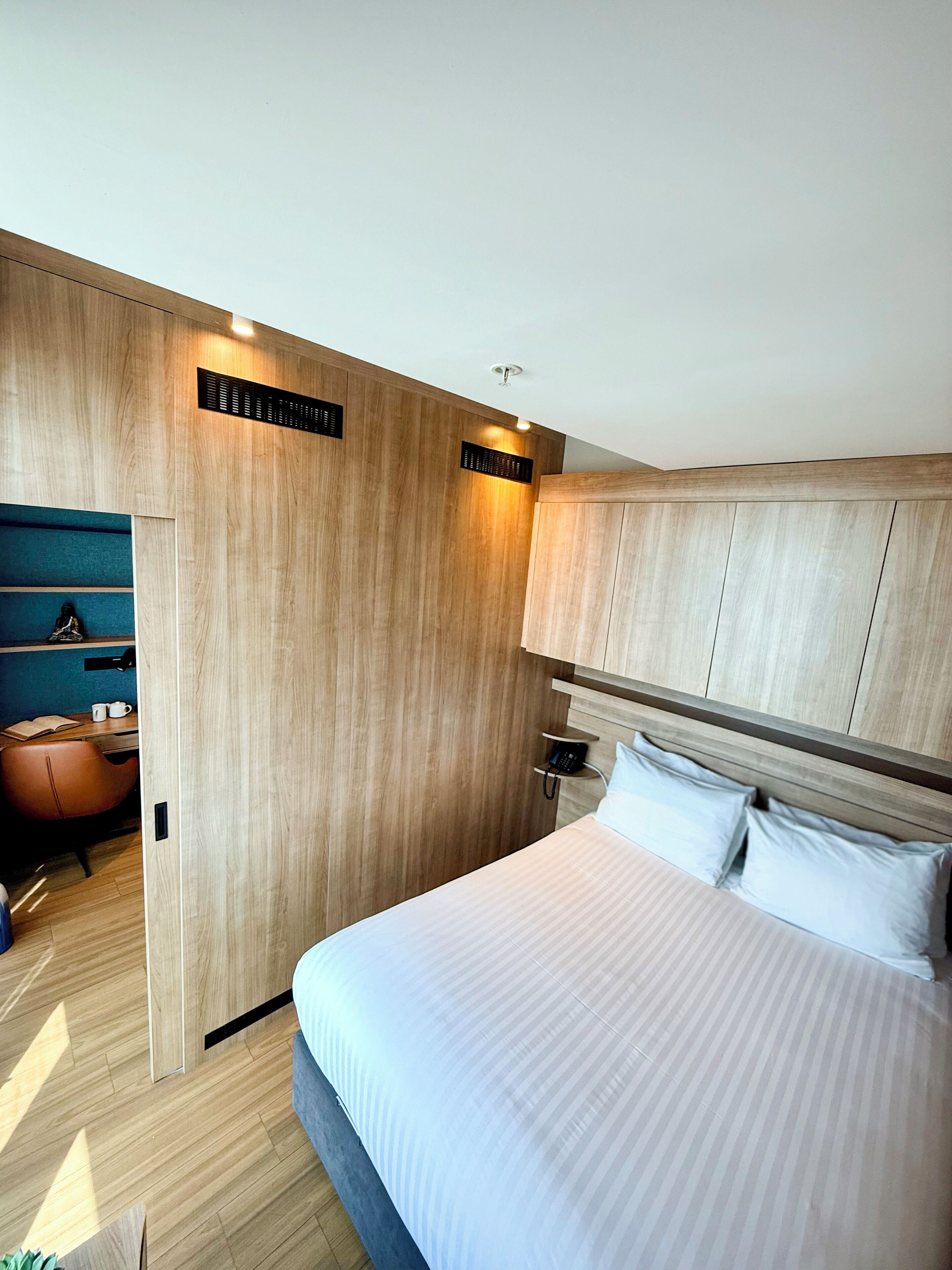 Ein modernes Schlafzimmer mit einem großen Bett, einem Holz-Kopfteil und einem Schreibtisch mit Stuhl.