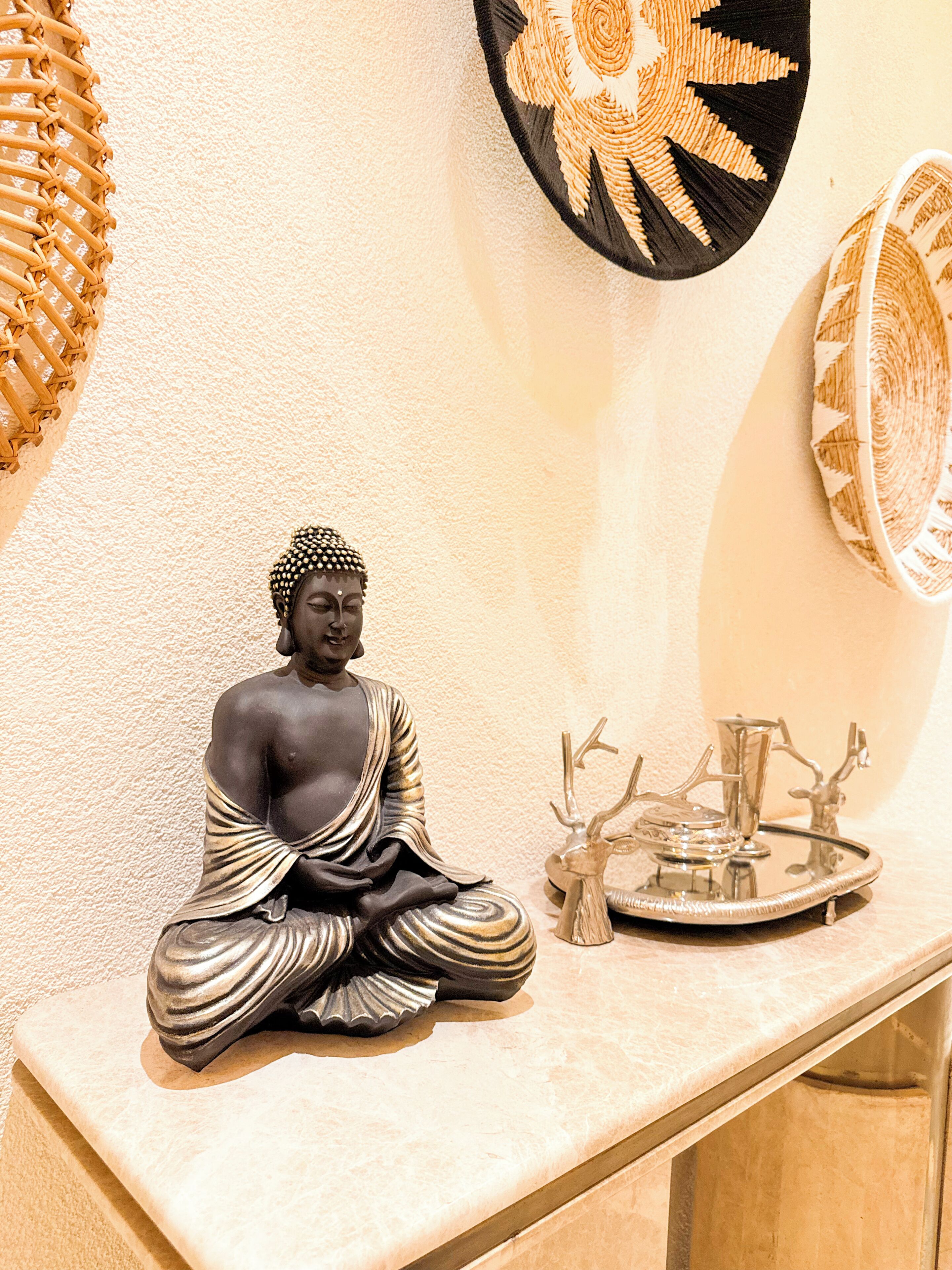 En statue af en siddende figur i en meditativ stilling på en marmorflade.
