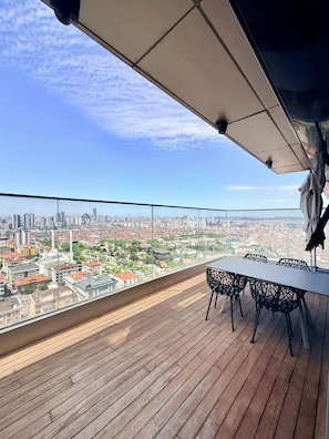 A rooftop terrace with a table and chairs, offering a panoramic city view. - Cityloft175 (Istanbul)