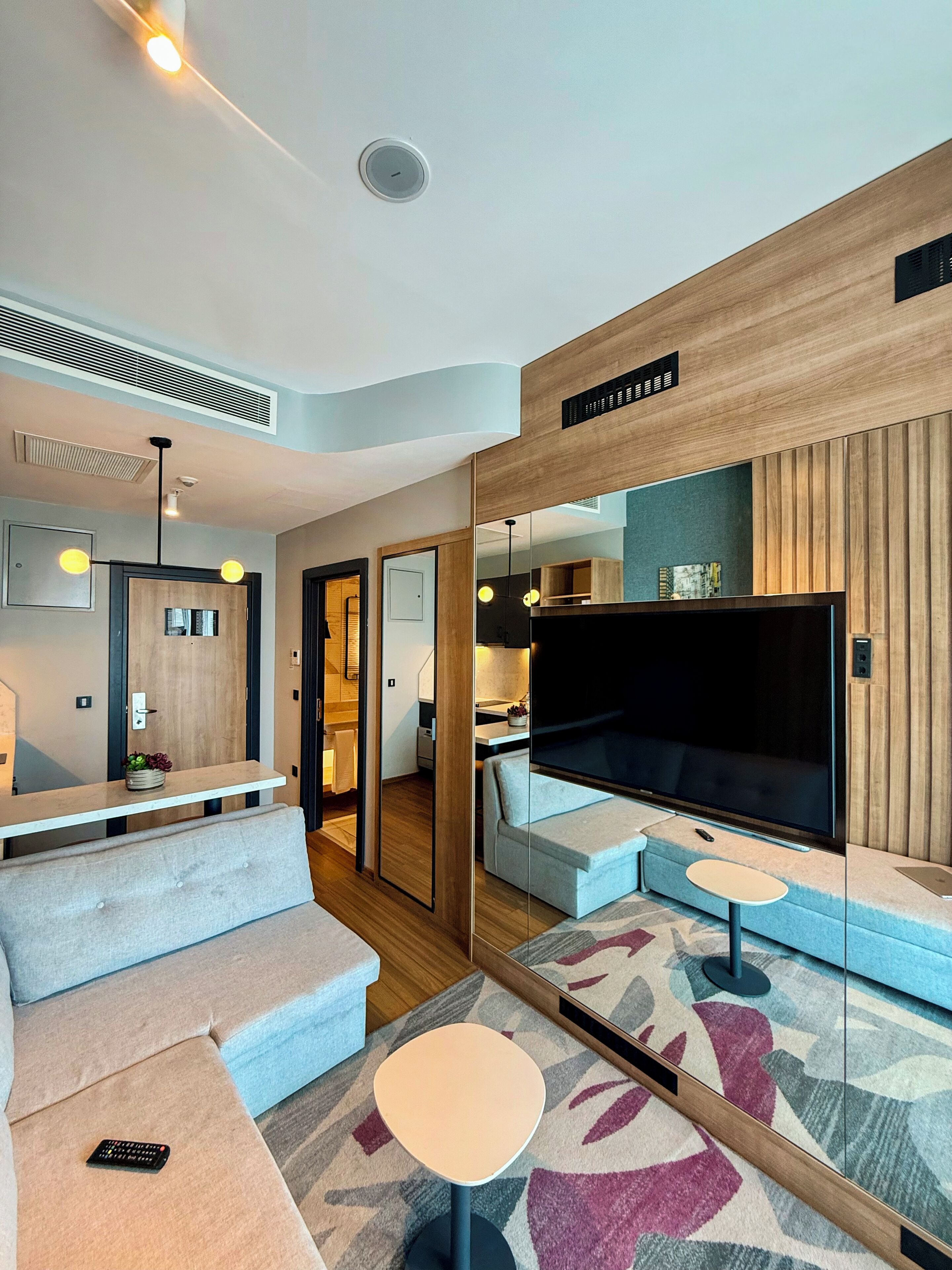 Una sala de estar moderna con un sofá, un televisor, una mesita y un espejo.