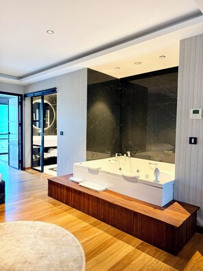 A modern bathroom with a large bathtub, wooden vanity, and a glass shower enclosure.
