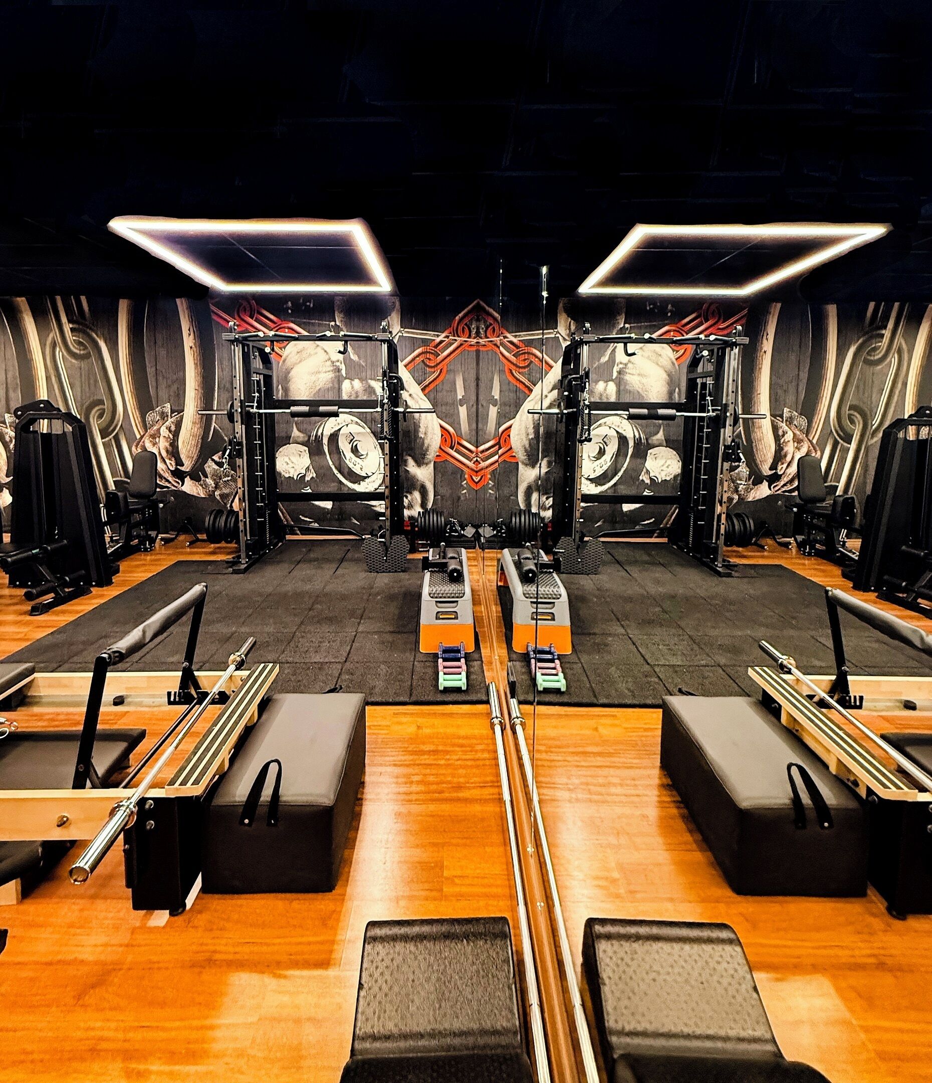 A gym with mirrored walls, exercise equipment, and a central weightlifting area.