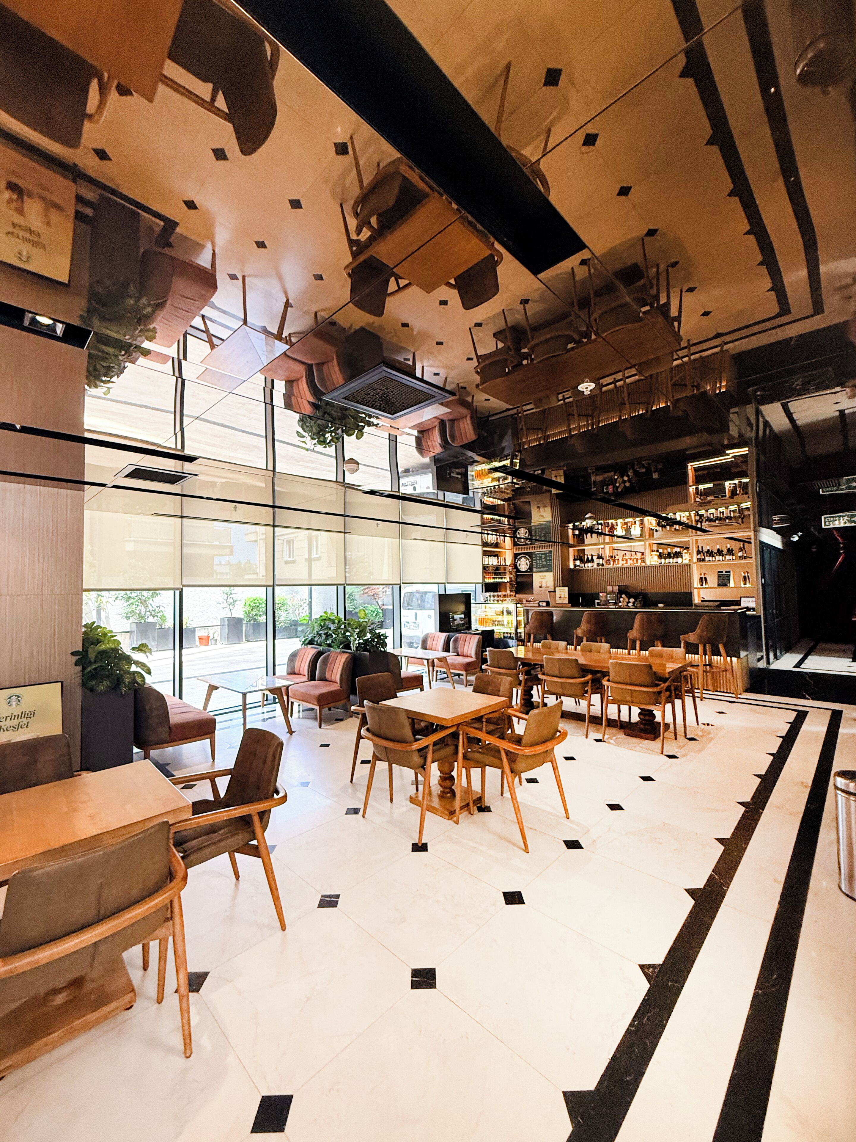 Un interior moderno con una zona de bar, asientos y vistas a través de amplios ventanales.
