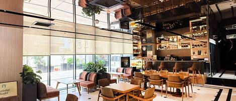 Un interior moderno con una zona de bar, asientos y vistas a través de amplios ventanales.