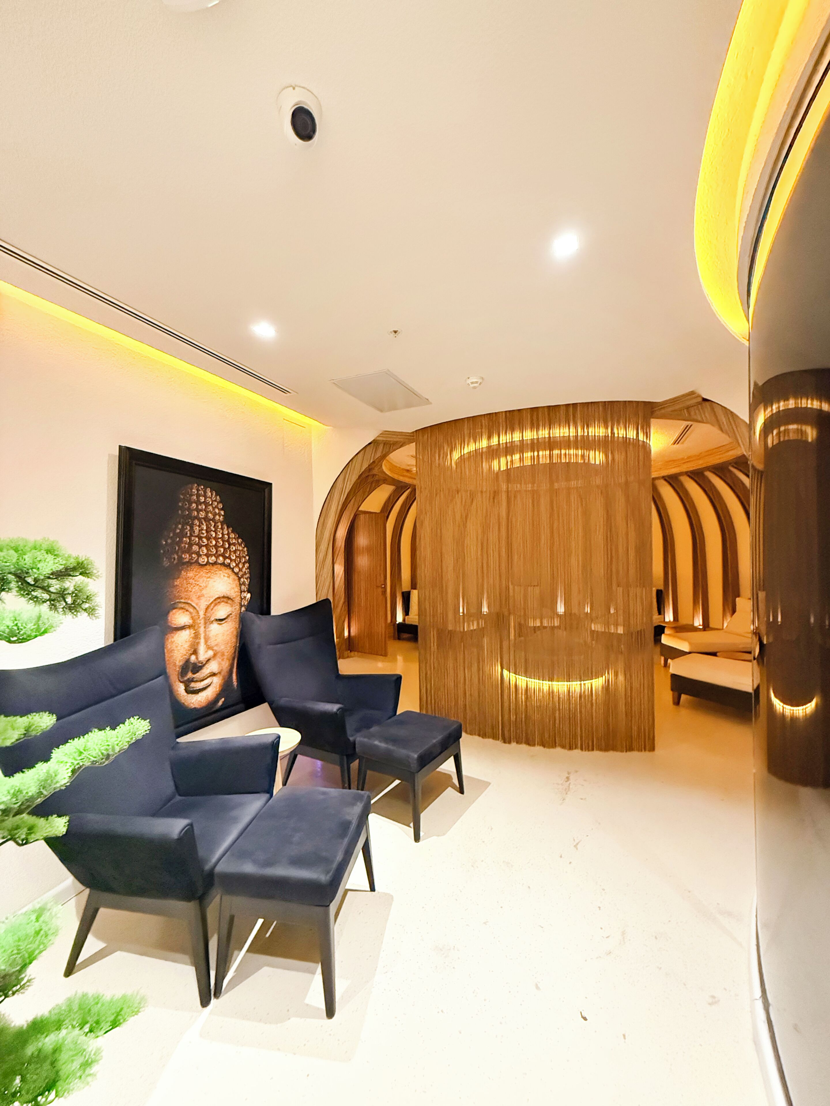 A modern interior with a Buddha statue, seating area, and a wooden partition.