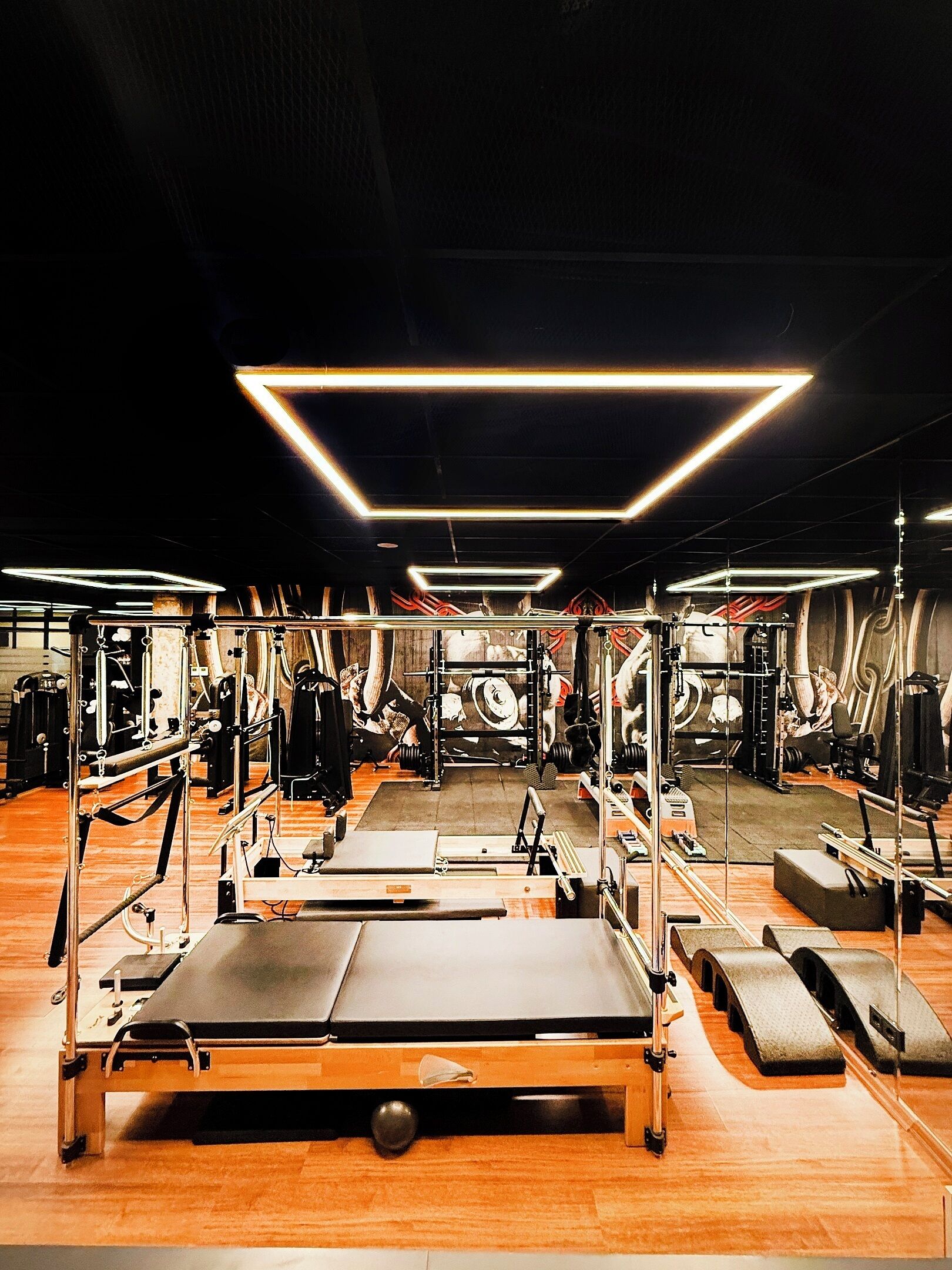 A gym with various exercise equipment, including treadmills, weight machines, and a Pilates reformer.